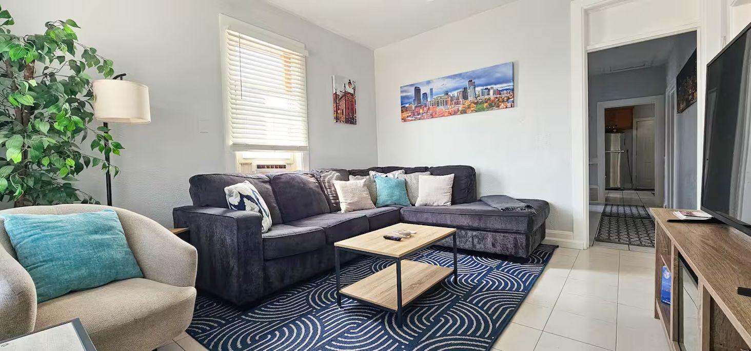 A modern living room with a sectional sofa, a coffee table, and a large plant.