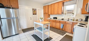 A kitchen with wooden cabinets, a stainless steel refrigerator, a white stove, and a small table with a vase. - 3BR Denver Home with Yard & Gated Parking (Denver)