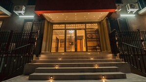 L'ingresso di un hotel con una scala che conduce a un cancello, affiancato da condizionatori e una recinzione metallica.