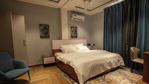 Camera d'albergo con un letto, una sedia, un comodino e un condizionatore.