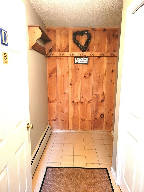 A hallway with wooden paneling, a heart-shaped wreath, and a sign that says "Please feel free to smoke outside." - Official Seasons RMC Condo 18D - 2 bedrooms - sleeps 4 - No Fees (Bartlett)