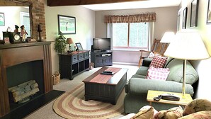 Ein Wohnzimmer mit Kamin, Fernseher, Sofa und Lampe.