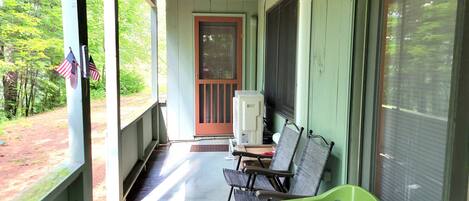 A porch with two chairs, a bench, and a small table.