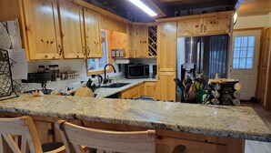 A kitchen with wooden cabinets, granite countertops, a stainless steel refrigerator, and a microwave.