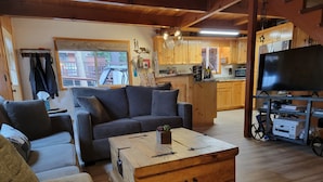 A cozy living room with a sofa, a coffee table, and a TV stand.
