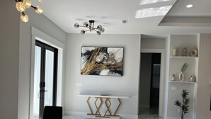 A modern dining area with a marble floor, a white console table, and a contemporary chandelier. - Upscale Getaway (Rotonda West)