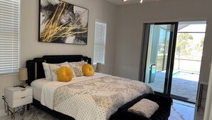 A modern bedroom with a large bed, a bench, a nightstand, and a ceiling light. - Upscale Getaway (Rotonda West)