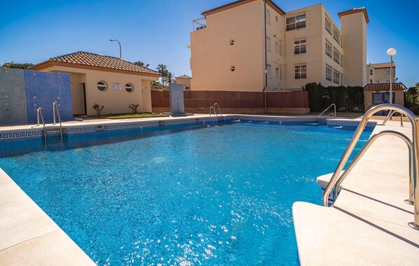 A swimming pool with clear blue water, surrounded by a tiled deck and a building with a tiled roof. - Nice apartment in Torrox with swimming pool (Torrox)