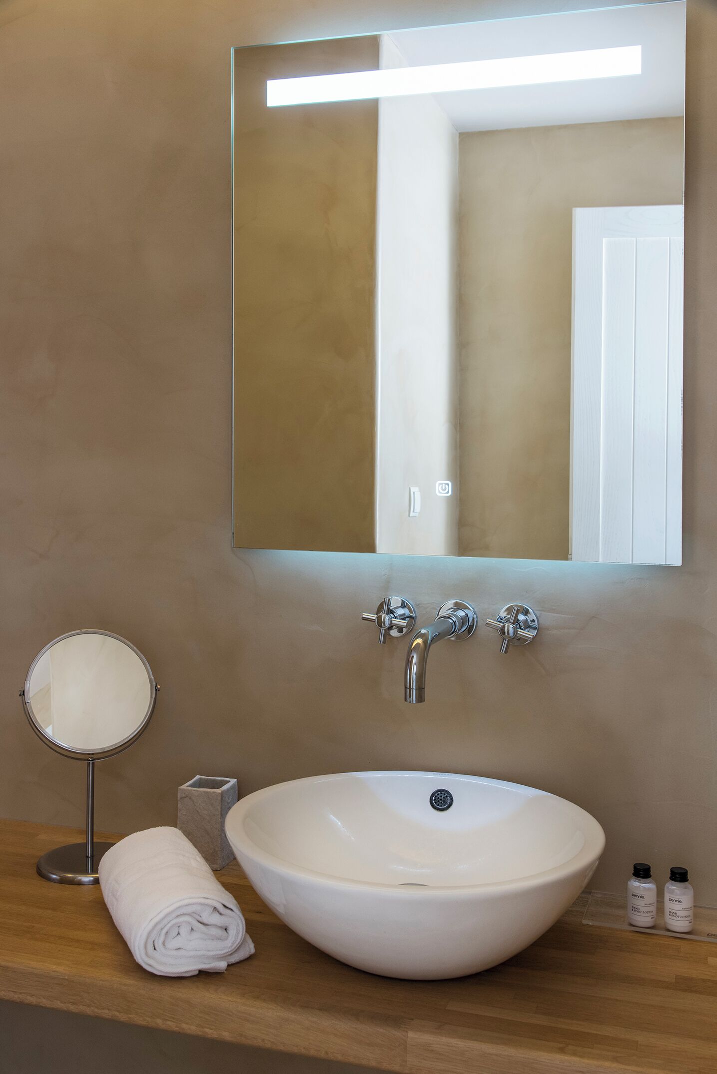 A bathroom with a white sink, a round mirror, and a rectangular mirror above it.
