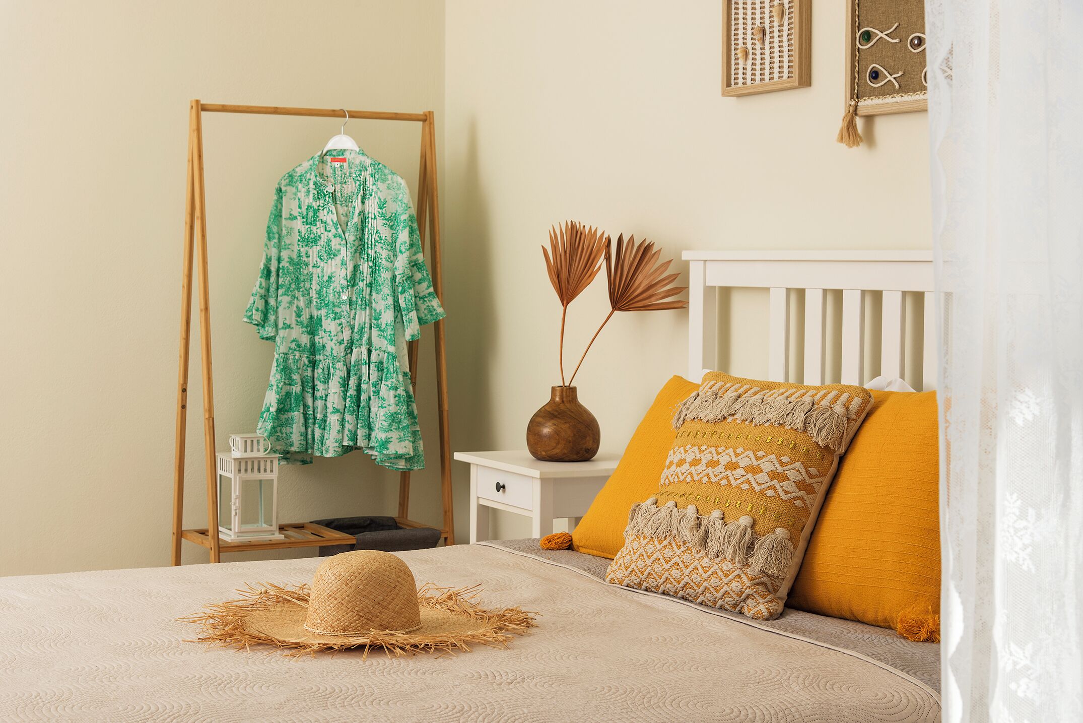 A neatly arranged bedroom with a bed, a wooden wardrobe, a bedside table with a vase, and a wall decoration.