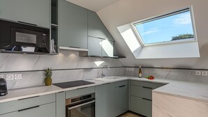 Una cocina moderna con horno empotrado, microondas y tragaluz.
