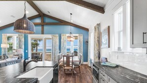 Una cocina con una isla grande, una mesa de comedor de madera y vistas al exterior.