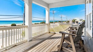 Una terraza de madera con vista a la playa y al océano.