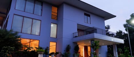 A modern two-story building with large windows, a balcony, and a well-lit entrance.