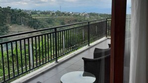 A balcony with a view of a green landscape and distant buildings. - Nava Magnolia Hotel (Bandung)