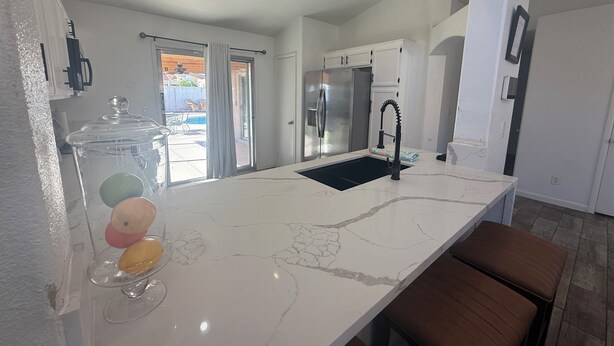 Una cocina moderna con encimera de mármol, electrodomésticos de acero inoxidable y un amplio ventanal.