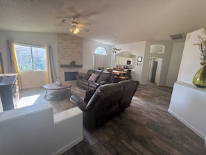 A living room with a leather sofa, a dining table, and a kitchen in the background. - Sunny Pool Retreat-Sleeps 11* RV Parking (North Las Vegas)