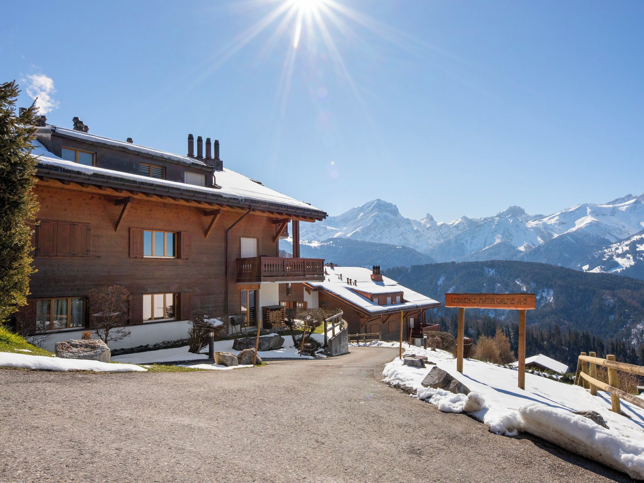 A wooden lodge with a balcony, a sign reading 'Residence Martin Gaipe A.D.', and a mountain view.