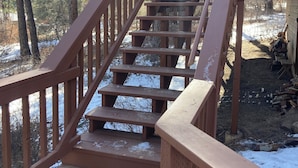 Eine Holztreppe führt zu einer Hütte in einem bewaldeten Gebiet mit Schnee.