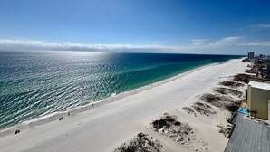 Una playa con cielo despejado, una orilla arenosa y edificios al fondo.
