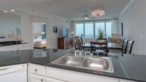 Una cocina moderna con una isla grande, un comedor con mesa y sillas, y vista al océano a través de amplios ventanales.