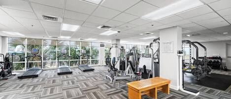 Un gimnasio con cintas de correr, máquinas de pesas y una banca.