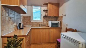Una cocina compacta con armarios de madera, un microondas, un fregadero y un refrigerador pequeño.