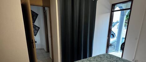 A bedroom with a bed, a door leading to a balcony, and a view of a parked car outside.
