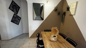 A dining area with a wooden table, black chairs, and a tiled floor. There are two abstract wall art pieces and a potted plant on the wall. - Comfortable family home between waterfalls and heavenly beaches (Petit-Bourg)