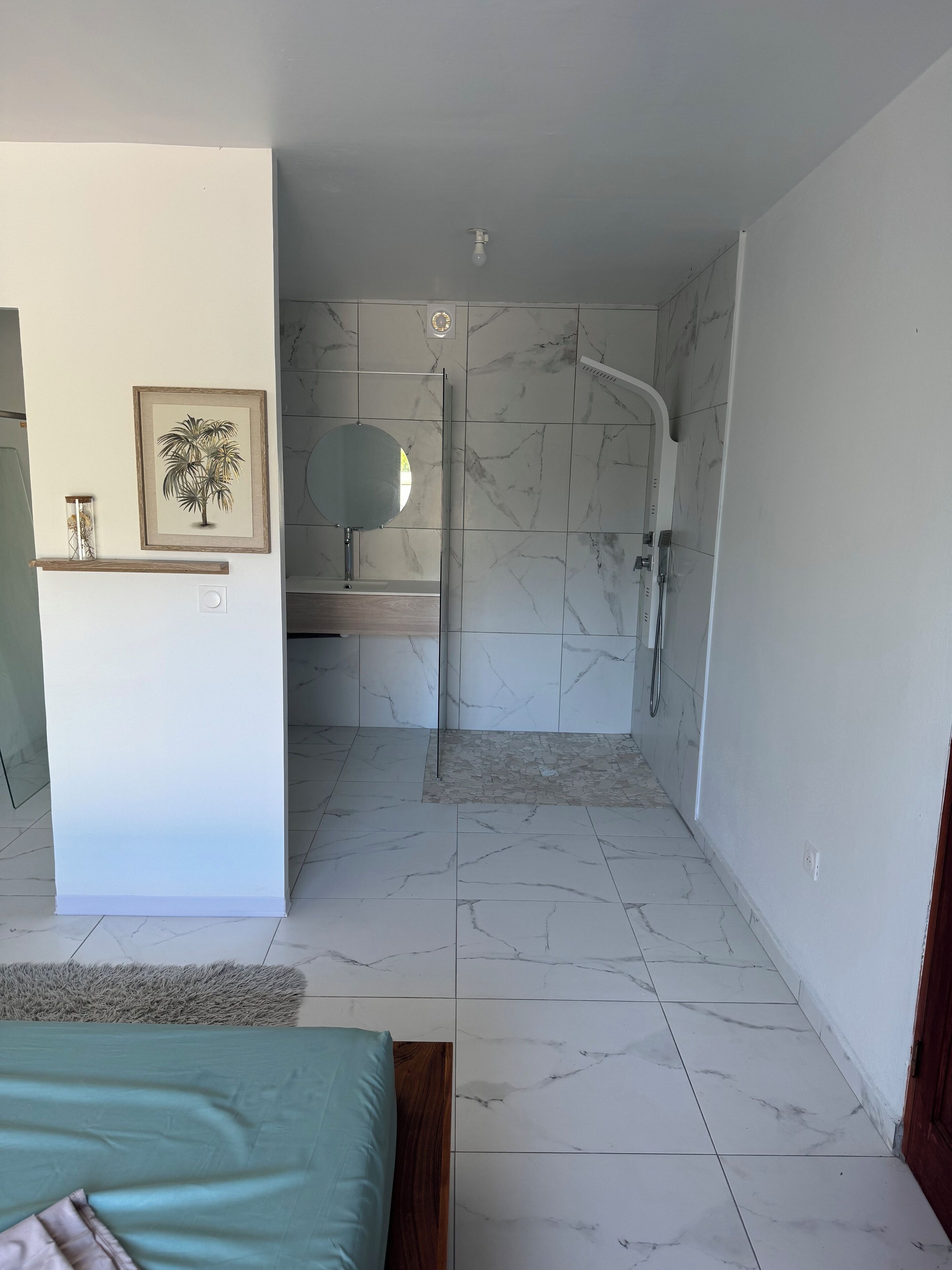 Ein modernes Badezimmer mit Dusche, Spiegel und einem gerahmten Bild an der Wand.