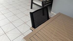A patio area with a table and two chairs, a tiled floor, and a view of the kitchen in the background. - Comfortable family home between waterfalls and heavenly beaches (Petit-Bourg)