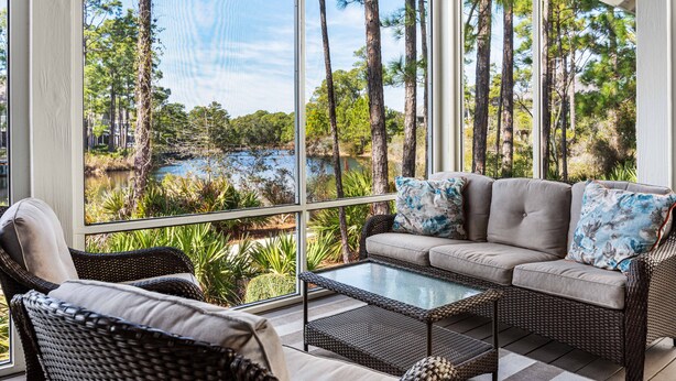 A sunlit room with large windows, a sofa, a chair, and a coffee table.