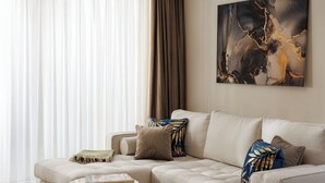 Ett modernt vardagsrum med en beige soffa, två runda soffbord och en stor, abstrakt tavla på väggen.