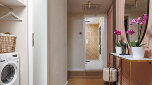 Ett utrymme för tvätt med en tvättmaskin, en torkställning och en liten papperskorg.