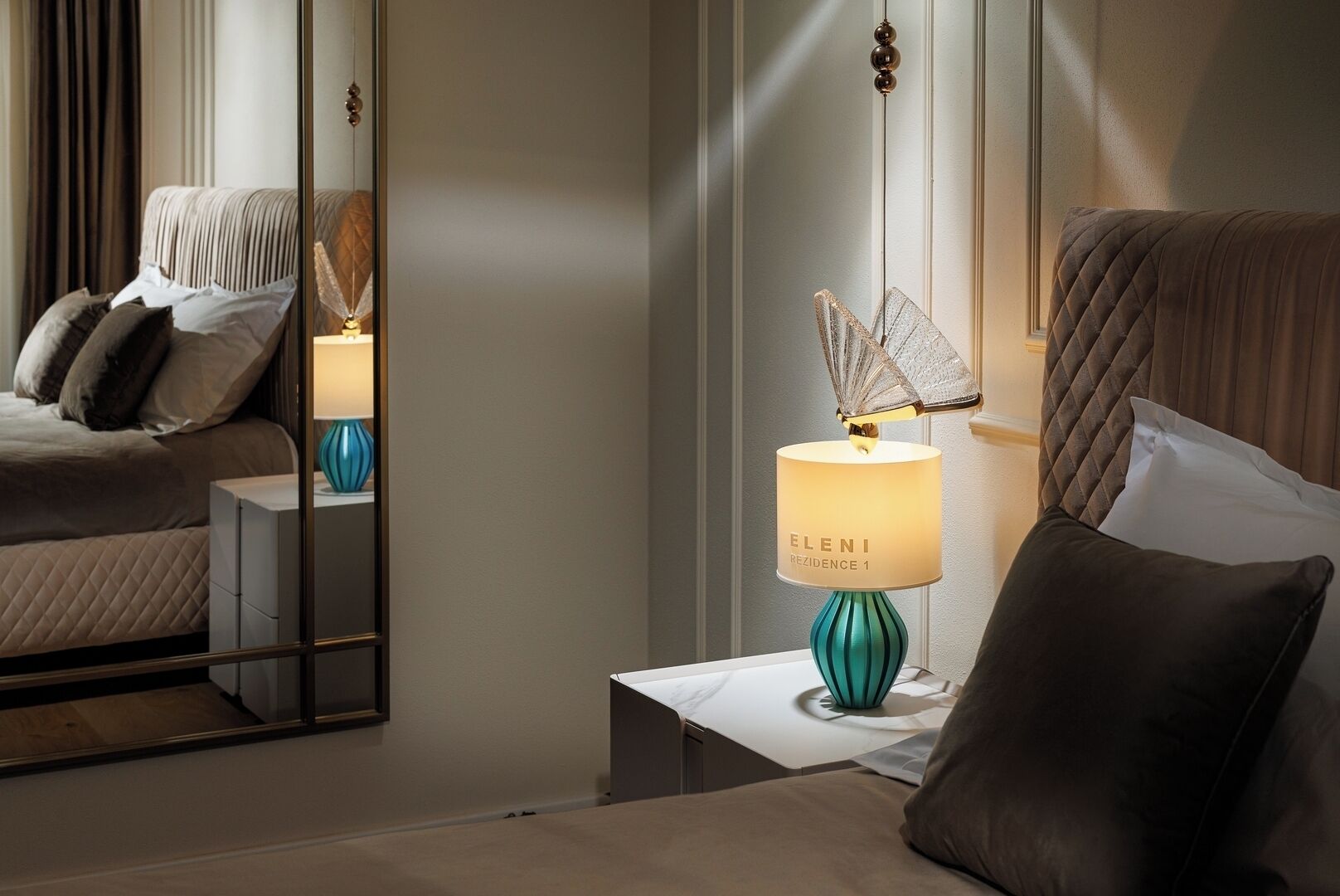 Ein Hotelzimmer mit einem Bett, einem Nachttisch mit Lampe und einem Spiegel, der den Raum widerspiegelt.