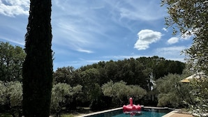 A swimming pool with a wooden deck, surrounded by trees and a clear sky. - Charming 4-bedroom Villa with AC, WiFi in lovely L'Isle-sur-la-Sorgue (L'Isle-sur-la-Sorgue)