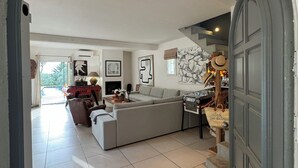 A spacious living room with a grey sofa, a piano, and a staircase leading to a second floor. - Charming 4-bedroom Villa with AC, WiFi in lovely L'Isle-sur-la-Sorgue (L'Isle-sur-la-Sorgue)