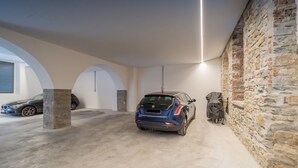 Un estacionamiento con un coche azul, paredes de piedra y un diseño moderno en el techo.
