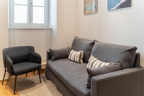 Una sala de estar moderna con un sofá gris, un sillón a juego y cojines a rayas.