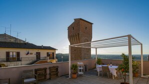 Terraza en la azotea con pérgola, mobiliario y plantas en macetas.