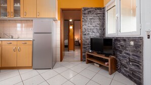 A compact kitchen with a refrigerator, wooden cabinets, and a stone accent wall.