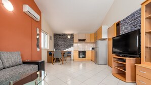 A modern kitchen with a built-in oven, a refrigerator, and a large TV on a wooden stand. - Apartment Julia A2, 2+2 (Biograd na moru)