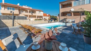 A poolside area with lounge chairs, a table with cups, and a view of the pool. - Apartment Julia A5, 2+2 (Biograd na moru)