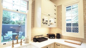 Una cocina con armarios blancos, un lavamanos y una ventana con vistas a un patio trasero.