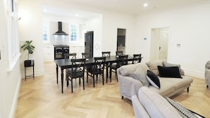 Una sala de estar moderna con comedor, un sofá y una cocina al fondo.