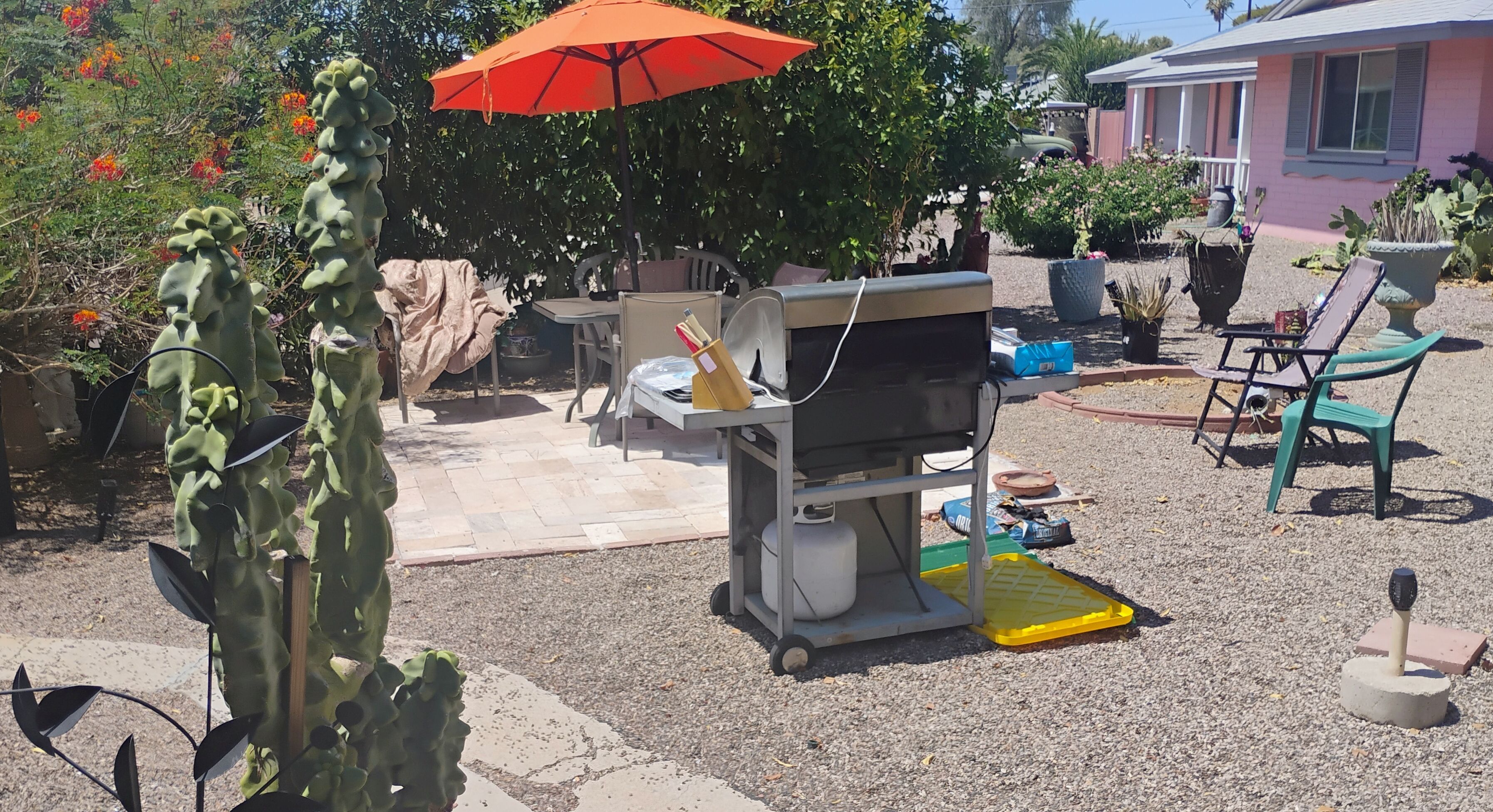 A patio area with a barbecue grill, outdoor furniture, and potted plants.