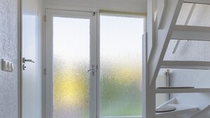 Een kamer met een grote schuifglazen deur die uitkomt op een balkon, een houten vloer en een witte trap.