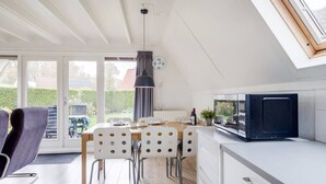 Een moderne keuken met een eetgedeelte, grote ramen en uitzicht op de omgeving.