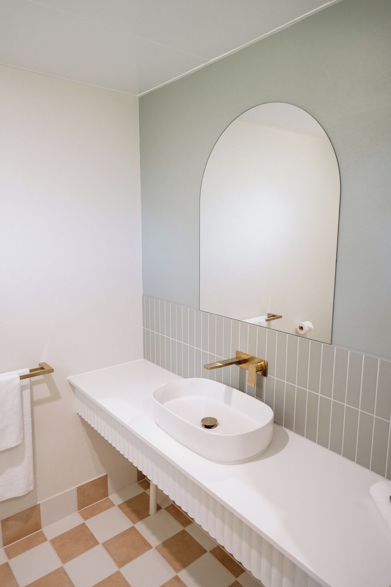 Ein Badezimmer mit Waschbecken, großem Spiegel und Handtuchhalter.