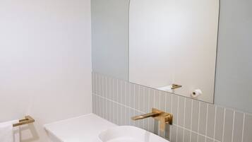 A bathroom with a white sink, a large mirror, and a towel rack.